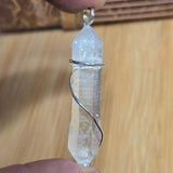 Crystal pendant held between two fingers against a wooden background