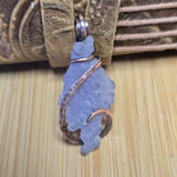 Lavender purple stone pendant with copper wire wrapping on a wooden surface