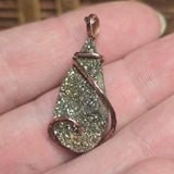 Sparkly pendant held between fingers with a blurred background