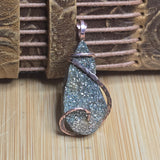 Teardrop-shaped pendant with glittery texture on a textured surface