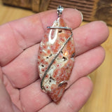 Orbicular Jasper pendant with silver chain held in a hand