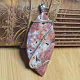 Jasper pendant with silver wire wrapping on a wooden surface