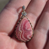 Pink stone pendant held in a hand