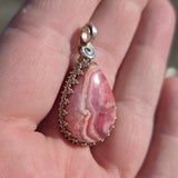 Pink marbled stone pendant with silver frame held in hand