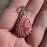 Pink stone pendant held in a hand