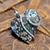 Decorative pendant with floral pattern on a textured wooden surface