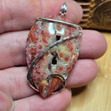 Close-up of a hand holding a unique stone pendant with intricate design.