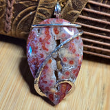 Jasper pendant with silver accents on a wooden surface