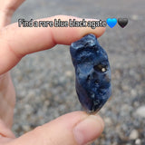 Hand holding a blue black agate stone with text overlay on a blurred background
