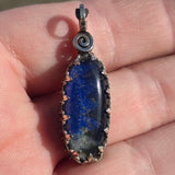 Blue stone pendant with silver setting held in a hand