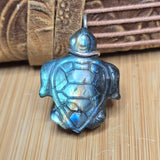 Turtle-shaped pendant with labradorite stone on a wooden surface