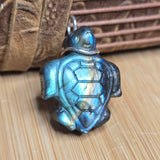 Turtle-shaped pendant with a metallic sheen on a wooden surface