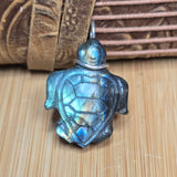 Turtle-shaped pendant with labradorite stone on a wooden surface