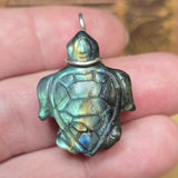Turtle-shaped pendant held in a hand with a blurred background