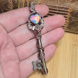 Decorative key pendant held in hand against neutral background