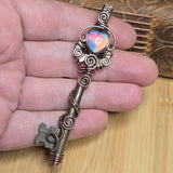 Decorative key pendant held in hand against neutral background