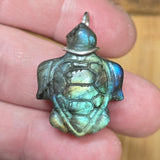 Turtle-shaped pendant with labradorite-like stone held between fingers