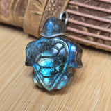 Turtle-shaped pendant with metallic sheen on a wooden surface