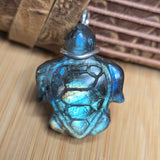 Turtle-shaped pendant with metallic sheen on a wooden surface
