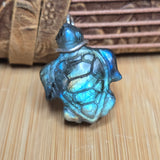 Turtle-shaped pendant with a metallic sheen on a wooden surface