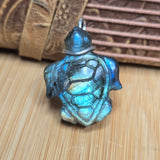 Turtle-shaped pendant with labradorite-like pattern on a wooden surface