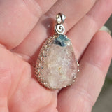 Crystal pendant held in a hand with a blurred background