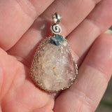Crystal pendant held in a hand with a blurred background