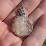 Crystal pendant with silver setting held in a hand