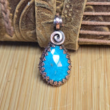 Turquoise pendant with a spiral design on a textured surface
