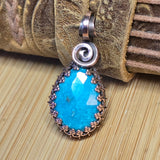 Pendant with blue stone and copper spiral on a textured surface