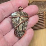 Hand holding a unique pendant with intricate design