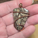 Hand holding a decorative stone with embedded coins and copper wire