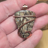 Hand holding a unique stone pendant with intricate patterns