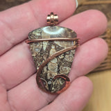 Hand holding a decorative pendant with intricate design