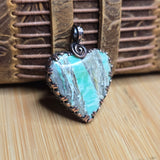 Variscite stone pendant with silver setting on a wooden surface