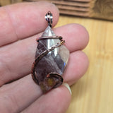 Crystal pendant held between fingers on a wooden surface