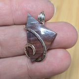 Purple jasper pendant with silver and copper accents held between fingers