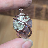 Hand holding a copper and stone ring with a blurred background