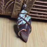 Pendant with brown and green stone on a wooden surface