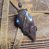 Purple stone pendant on a textured brown leather surface