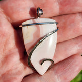 Hand holding a white stone pendant with silver accents