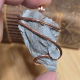 Copper wire wrapped around a gray stone on a blurred background