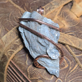Pendant with blue stone and copper wire on a textured brown background