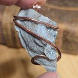 Copper-wrapped crystal on a blurred natural background