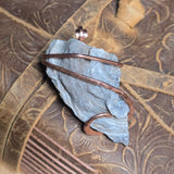 Pendant with blue stone and copper wire on a textured bronze background