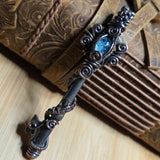 Antique skeleton key wire wrap pendant with aquamarine accent against a leather book on a wood surface