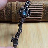 Antique skeleton key wire wrap pendant with aquamarine accent against a leather book on a wood surface