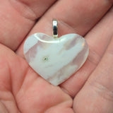 Heart-shaped stone pendant held between fingers